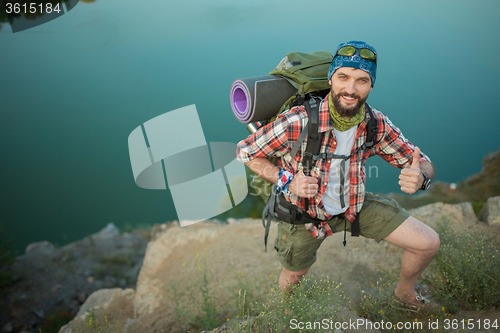 Image of Young caucasian man with backpack climbing the rock