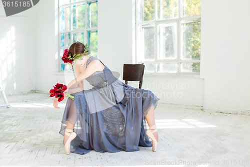Image of The beautiful ballerina sirtting in long gray dress 