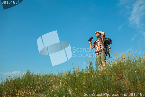 Image of Young caucasian man with backpack standing on the top of hill