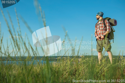 Image of Young caucasian man with backpack standing on the top of hill