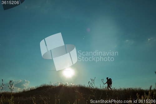 Image of Young caucasian man with backpack walking on a green meadow