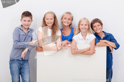 Image of Happy smiling group of kids, boys and girls, showing board 