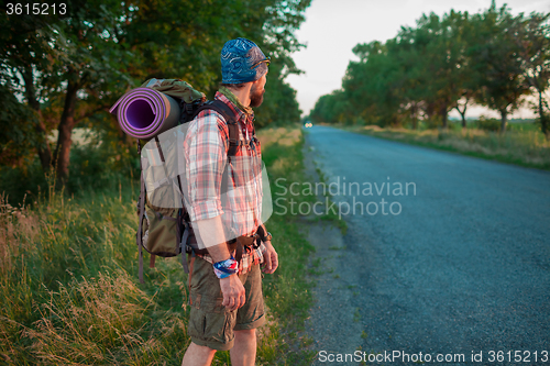 Image of Young caucasian tourist hitchhiking along a road.