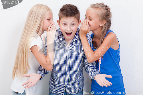 Image of Teenage girsl whispering in the ears of a secret teen boy on white  background