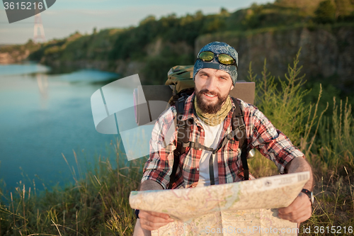 Image of Young caucasian man with backpack sitting on the top of hill