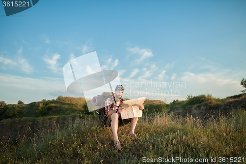 Image of Young caucasian man with backpack sitting on the top of hill