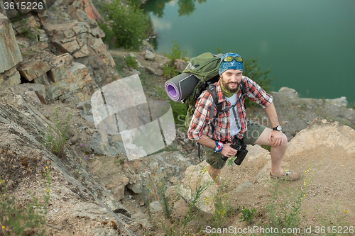 Image of Young caucasian man with backpack climbing the rock