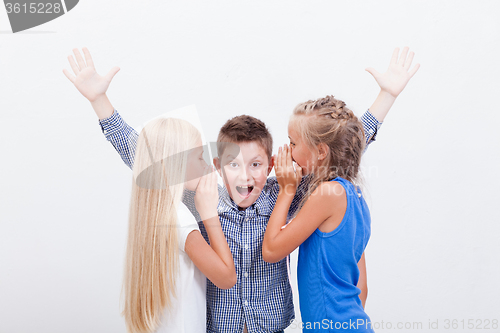 Image of Teenage girsl whispering in the ears of a secret teen boy on white  background