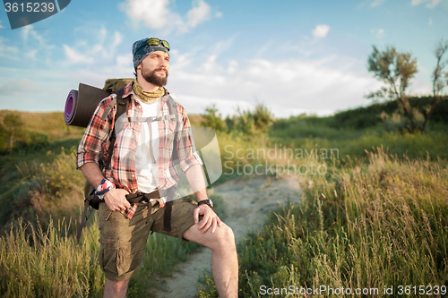 Image of Young caucasian man with backpack walking on the top of hill