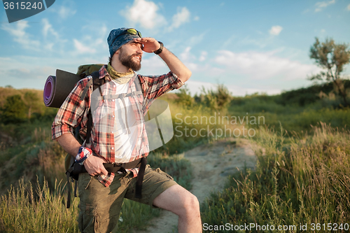 Image of Young caucasian man with backpack walking on the top of hill