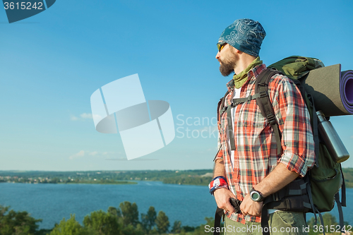 Image of Young caucasian man with backpack standing on the top of hill