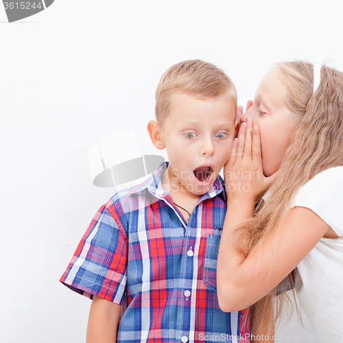 Image of Teenage girl whispering in the ear of a secret teen boys on white  background