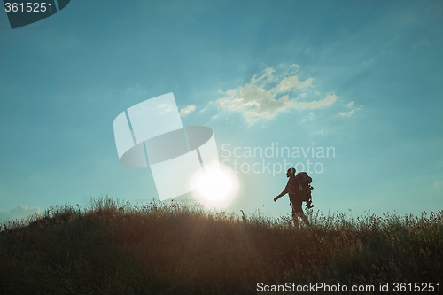 Image of Young caucasian man with backpack walking on a green meadow