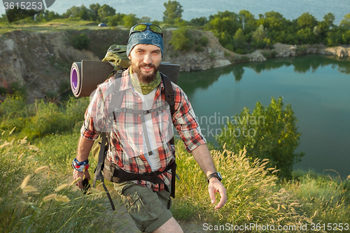 Image of Young caucasian man with backpack walking on the top of hill