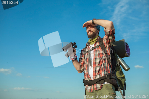 Image of Young caucasian man with backpack standing on the top of hill