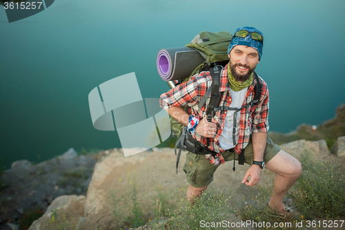 Image of Young caucasian man with backpack climbing the rock