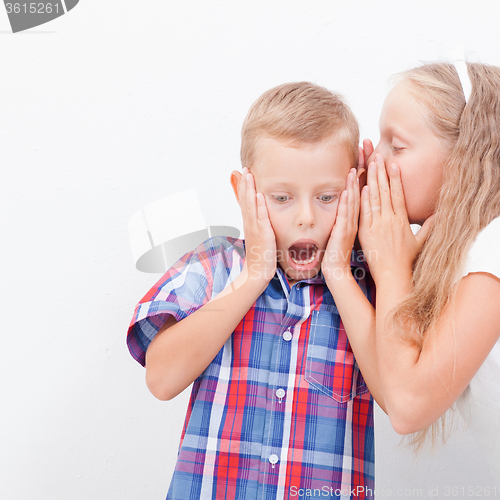 Image of Teenage girl whispering in the ear of a secret teen boys on white  background