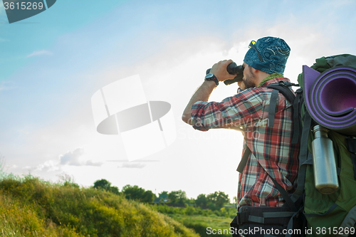 Image of Young caucasian man with backpack standing on the top of hill