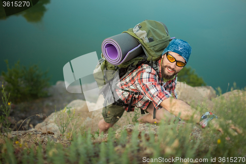 Image of Young caucasian man with backpack climbing the rock