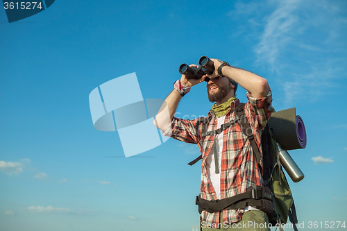 Image of Young caucasian man with backpack standing on the top of hill