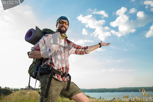 Image of Young caucasian man with backpack standing on the top of hill