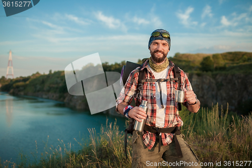 Image of Young caucasian man with backpack resting and drinking water