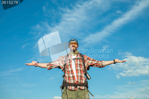 Image of Young caucasian man with backpack standing on the top of hill
