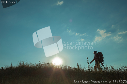 Image of Young caucasian man with backpack walking on a green meadow
