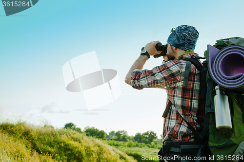 Image of Young caucasian man with backpack standing on the top of hill