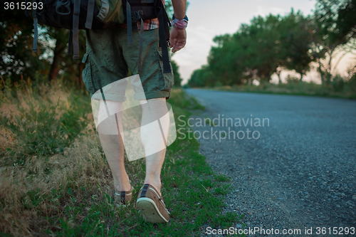 Image of Young caucasian tourist hitchhiking along a road.