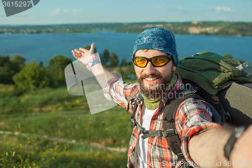 Image of Young caucasian man with backpack standing on the top of hill