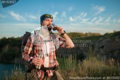 Image of Young caucasian man with backpack resting and drinking water