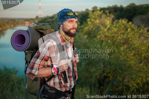 Image of Young caucasian man with backpack walking on the top of hill