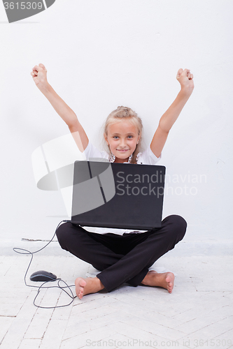 Image of young teen girl with arms raised using laptop