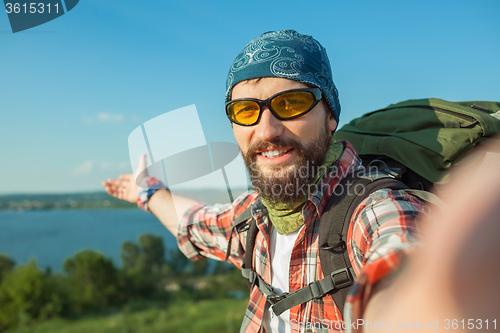 Image of Young caucasian man with backpack standing on the top of hill