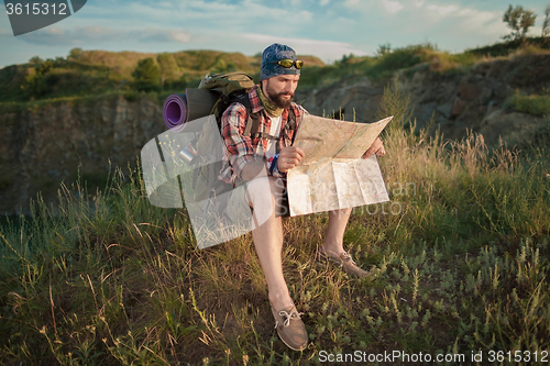 Image of Young caucasian man with backpack sitting on the top of hill