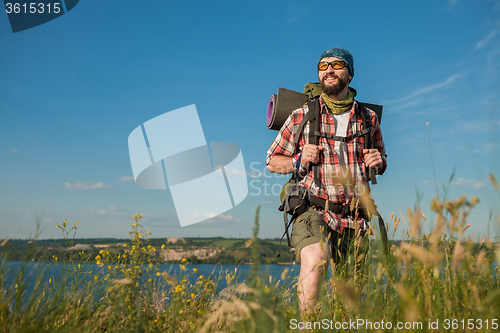 Image of Young caucasian man with backpack standing on the top of hill