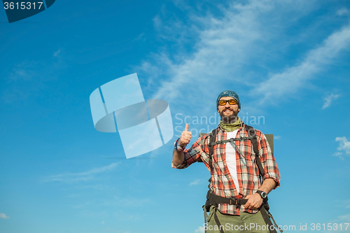 Image of Young caucasian man with backpack standing on the top of hill