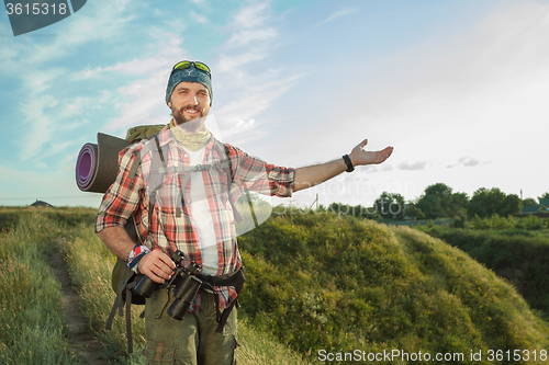 Image of Young caucasian man with backpack standing on the top of hill