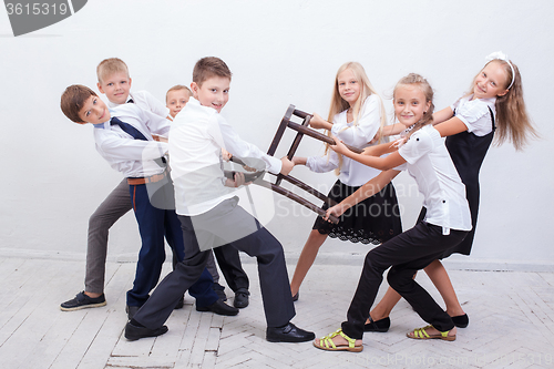 Image of Kids playing tug of chair - girls versus boys,