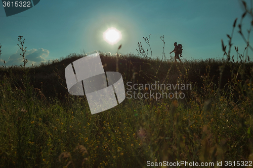 Image of Young caucasian man with backpack walking on a green meadow