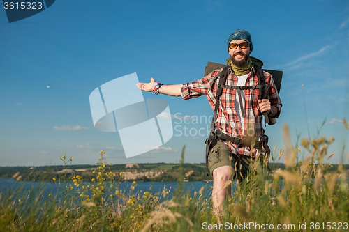 Image of Young caucasian man with backpack standing on the top of hill