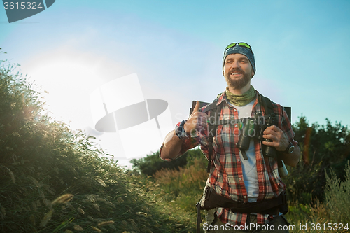 Image of Young caucasian man with backpack walking on a green meadow