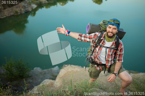 Image of Young caucasian man with backpack standing on the top of hill