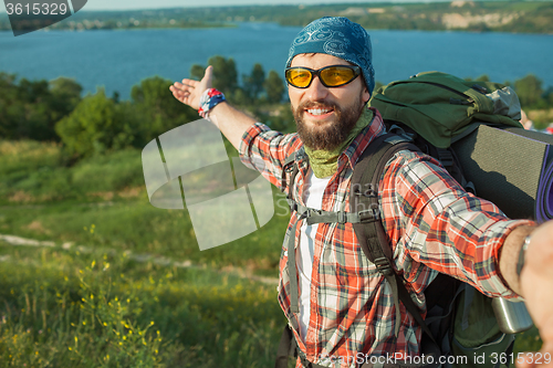 Image of Young caucasian man with backpack standing on the top of hill