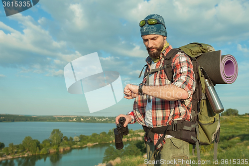 Image of Young caucasian man with backpack standing on the top of hill