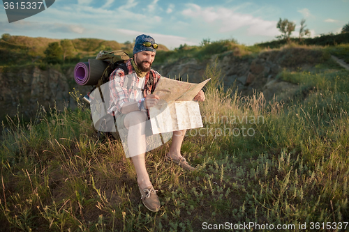 Image of Young caucasian man with backpack sitting on the top of hill
