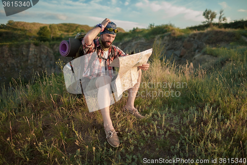 Image of Young caucasian man with backpack sitting on the top of hill