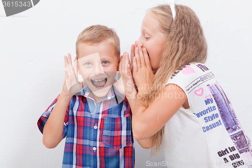 Image of Teenage girl whispering in the ear of a secret teen boys on white  background