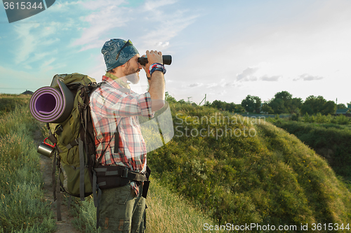 Image of Young caucasian man with backpack standing on the top of hill